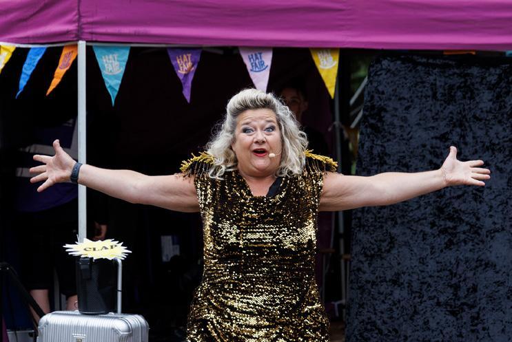 A performer in a sparkly dress with her arms out wide.