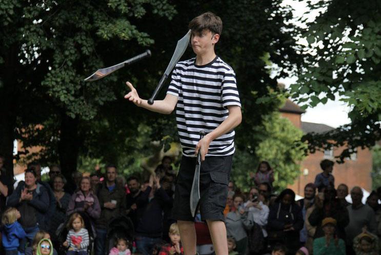 A young boy juggling in front of a crowd