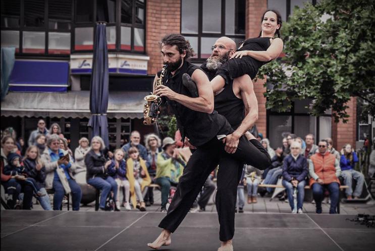 Three performers piggy-backing on each other in the street