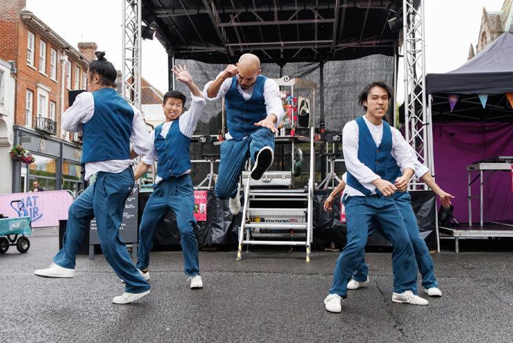 A group of performers dancing and doing acrobatics in front of a stage.