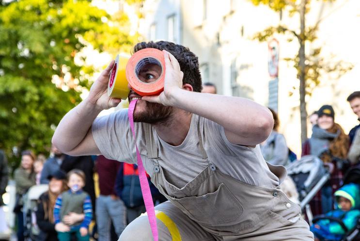 A performer playing with coloured tape