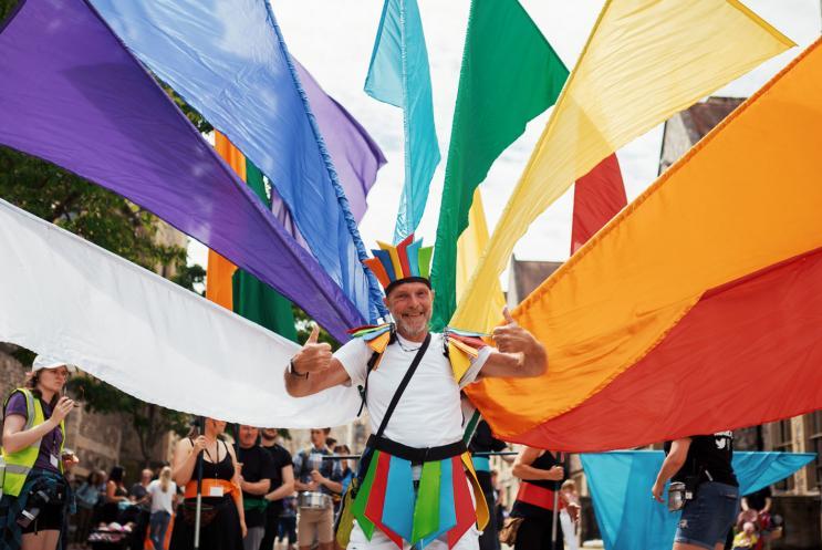 Happy man with his thumbs up leading the carnival with colourful flags